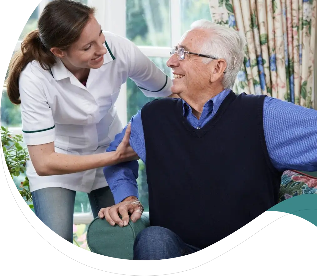 A woman is helping an older man sit on the couch.