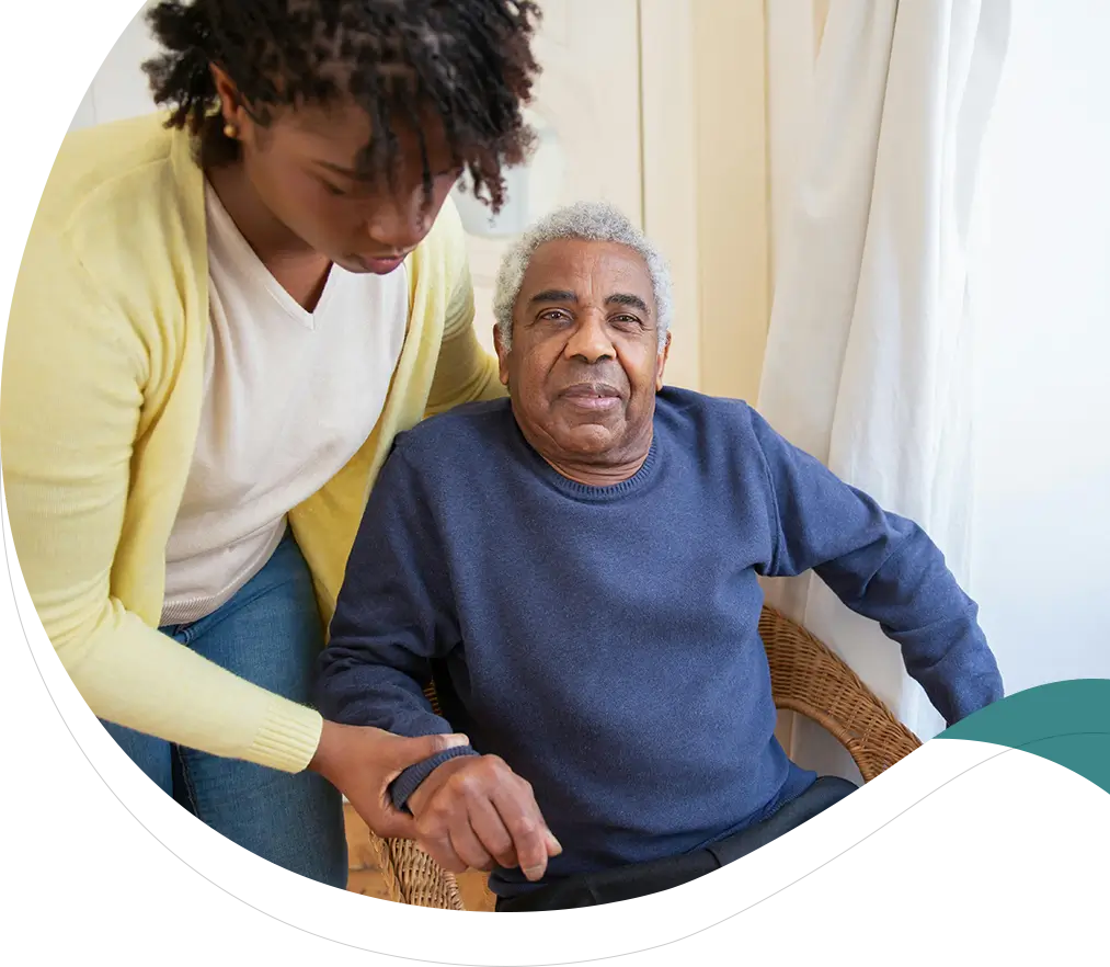 A woman helping an older man sit in his chair.